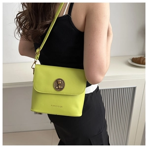 Détail d'un sac seau vert néon avec emblème d'ours en bronze et texture en cuir raffiné