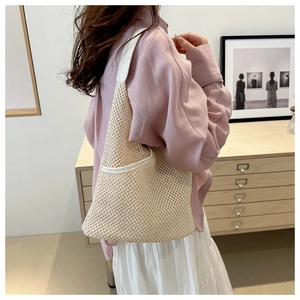Gros plan sur un sac en filet tissé beige avec bandoulière en cuir blanc en situation réelle