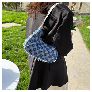 Gros plan du sac baguette en denim bleu à damier avec bords effilochés et sangle