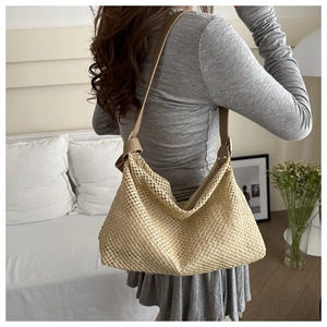 Detail of hand-woven straw tote bag with slim leather straps and soft textured finish