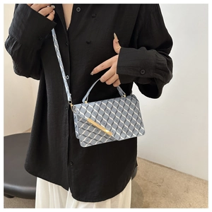 Detail of blue and white geometric crossbody bag with gold metal trim and strap