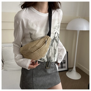 Detail of woven straw waist bag featuring metal zipper and adjustable black fabric strap