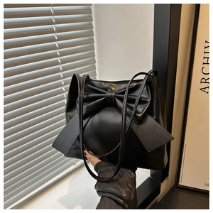 Détail de la texture en cuir noir lisse et grand nœud décoratif sur le sac cabas