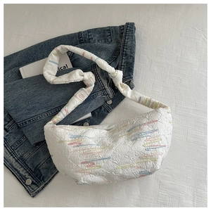 Gros plan sur un sac croissant blanc matelassé avec broderies ondulées et bandoulière
