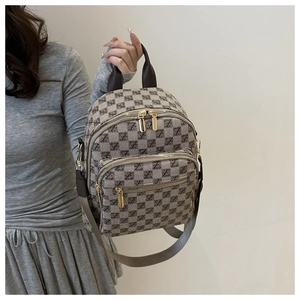 Close-up of checkerboard jacquard backpack with golden metal zippers and leather handles
