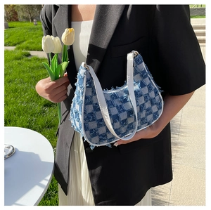 Détail du sac baguette en toile à damier bleu avec bords effilochés et anse blanche