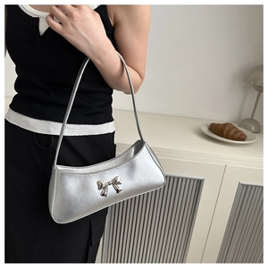 Detail of silver metallic butterfly knot and pearlescent leather on underarm bag