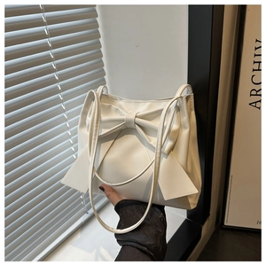 Détail d'un sac cabas blanc avec un grand nœud décoratif et fines doubles anses