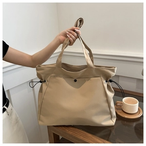 Detail of beige nylon tote bag featuring adjustable side drawstrings and magnetic pocket