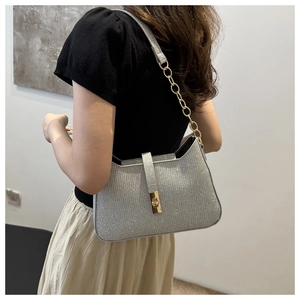 Détail d'un sac à bandoulière pailleté argenté avec chaîne dorée et fermoir rotatif
