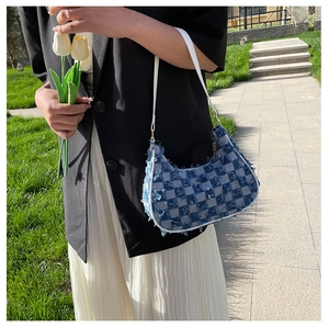 Détail du sac hobo en jean à damier avec bords effilochés et fine bandoulière blanche