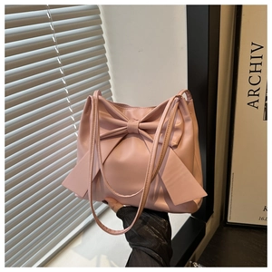 Détail d'un sac cabas rose tendre avec un grand nœud décoratif et une finition texturée