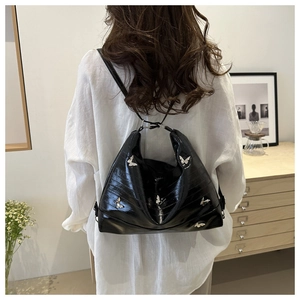 Detail of black glossy hobo bag with silver butterfly charms on a minimalist background