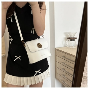 Détail du sac seau blanc avec emblème doré vintage et texte FANYISSA dans un cadre maison