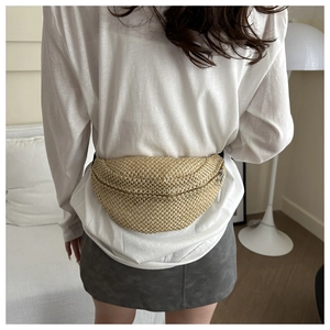 Détail du sac ceinture en paille tressée beige montrant la texture et la forme de selle