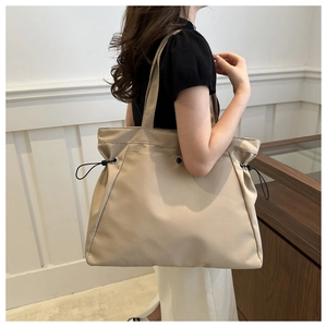 Detail of high-capacity beige tote bag featuring stylish side drawstring design and nylon fabric