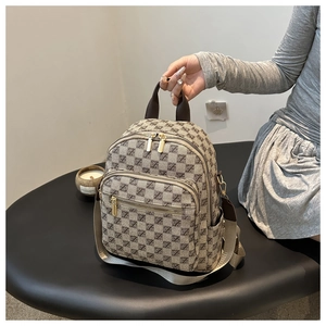 Detail of checkered pattern multi-pocket backpack with golden zippers on a black table