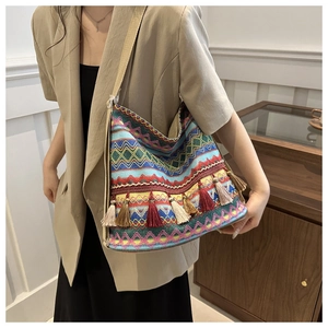 Detail of woven ethnic tote bag featuring colorful geometric patterns and long fringes