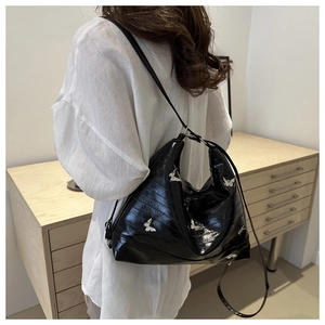 Detail of black glossy leather shoulder bag featuring silver metal butterfly ornaments