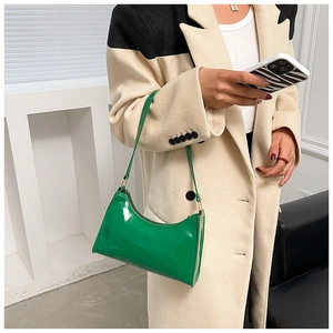 Detail showing the glossy lime green patent leather material and slim strap of the baguette bag