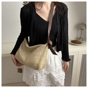 Détail d'un sac cabas en paille tissé main avec bandoulière en cuir brun et nœud déco