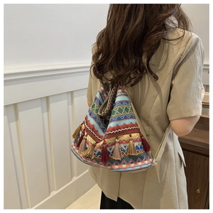 Rear view of a model wearing the bohemian woven tote bag with colorful fringe tassels