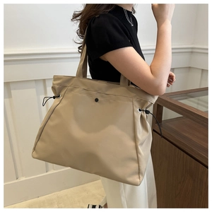 Detail of beige large capacity tote bag featuring black drawstring and snap closure