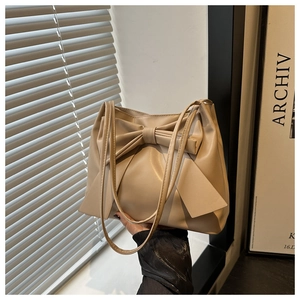 Détail d'un sac cabas beige avec un grand nœud décoratif et cuir synthétique souple