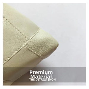 Dettaglio ravvicinato della borsa a secchiello beige con grana di pelle e cuciture rinforzate