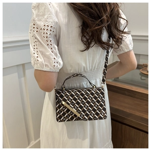 Detail of vintage geometric print shoulder bag with metallic bar buckle on a white dress