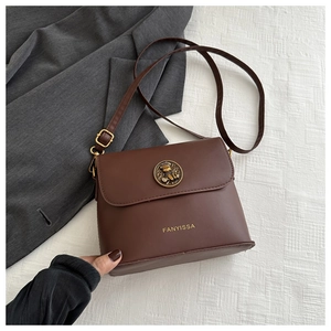Close-up of brown leather bag featuring an embossed bronze badge and FANYISSA logo