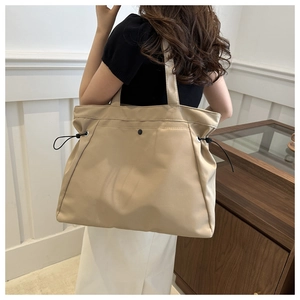 Detail of khaki canvas tote bag featuring black side drawstrings and smooth texture