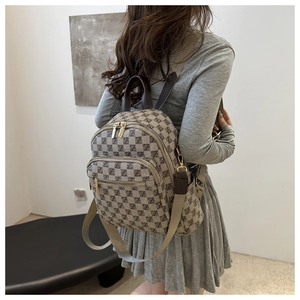 Close-up of stylish plaid mini backpack with gold zippers and adjustable textile straps