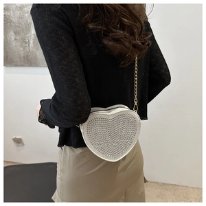 Detailed view of heart-shaped white crossbody bag with studded rhinestones and gold chain