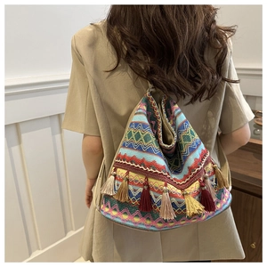 Detailed view of colorful ethnic knit tote bag featuring vibrant geometric patterns and long tassels