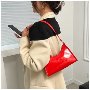 Glossy red patent leather half-moon baguette bag styled with a minimalist winter coat