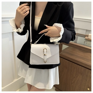 Chic light grey crossbody bag with gold buckle hardware on a model in professional attire