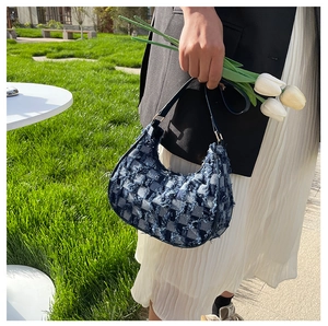 Détail du sac hobo en jean bleu avec texture en damier effiloché et bandoulière