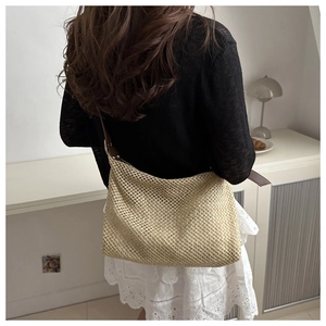 Détail du sac cabas en paille tressée avec bandoulière en cuir porté par un mannequin