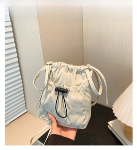 Close-up of white nylon drawstring crossbody bag with adjustable buckle in warm home setting