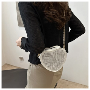 Detail showing white heart-shaped evening bag with silver rhinestones and gold chain strap