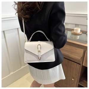 Close-up of a white leather envelope bag with gold buckle on a model's shoulder