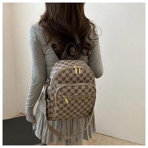 Detail view of checkered monogram backpack with gold zippers on a model's shoulder