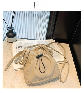 Detail of khaki nylon bucket bag with black drawstring closure on stone surface