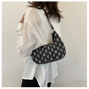 Détail du sac baguette en toile à damier noir et gris avec des bords effilochés stylés