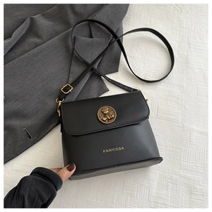 Macro shot of black leather trapezoid bag with golden embossed clasp and brand lettering