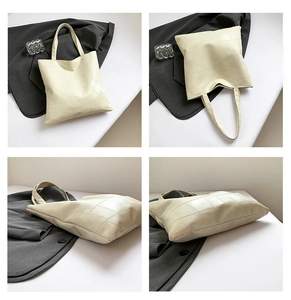 Dettaglio del motivo geometrico trapuntato e dei doppi manici della borsa beige