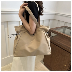 Detail view of large canvas tote bag with adjustable black drawstring on beige fabric