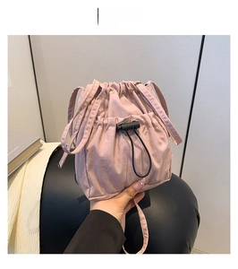 Detail view of pink nylon drawstring crossbody bag with pleated texture and black toggle