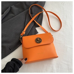 Close-up of orange leather bucket bag featuring antique gold hardware and a metal buckle